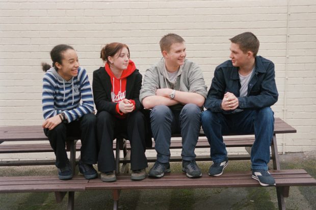 Happy teenagers sat on a bench