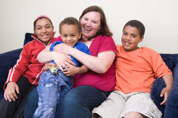 Mum and her happy young family sitting on the sofa together at home