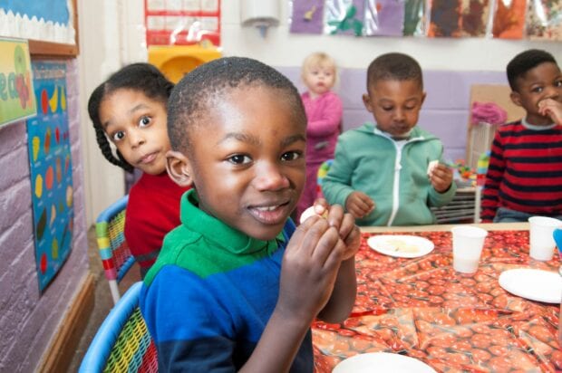 Pre-schoolers sitting around a table eating lunch