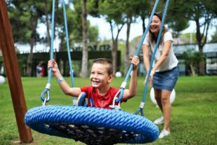 Carer pushing smiling boy in a swing