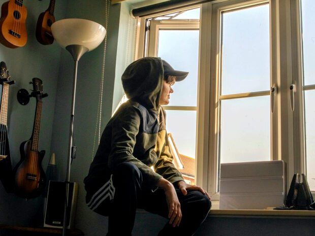 Boy sitting on window ledge looking outside