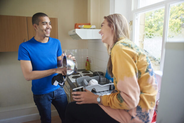 Young people chatting and laughing in a shared kitchen.